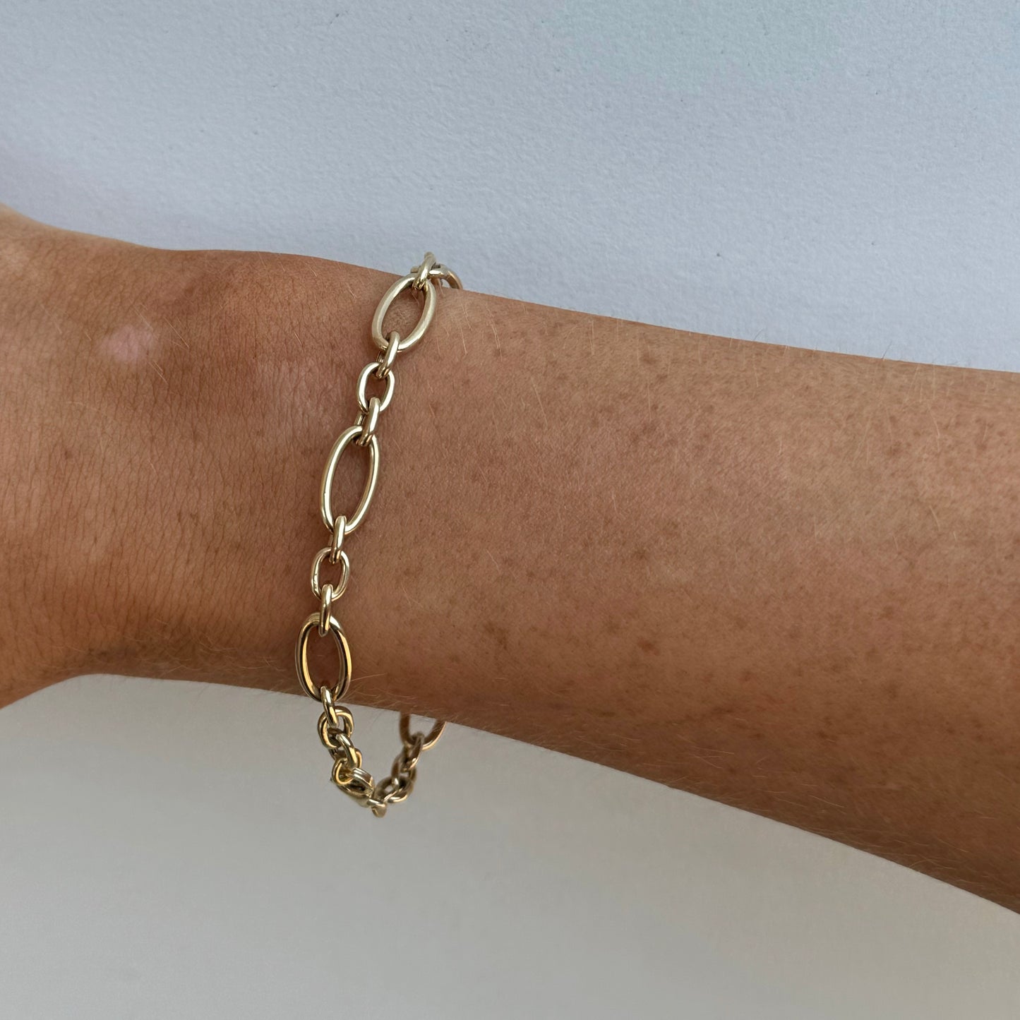 The BENJI Gold Bracelet by Dylan James Jewelry, crafted from 14kt yellow gold, adorns a person's wrist against a light gray background.