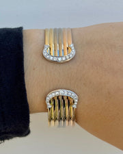 Gold and silver bracelet with fringe design on a wrist against a neutral background
