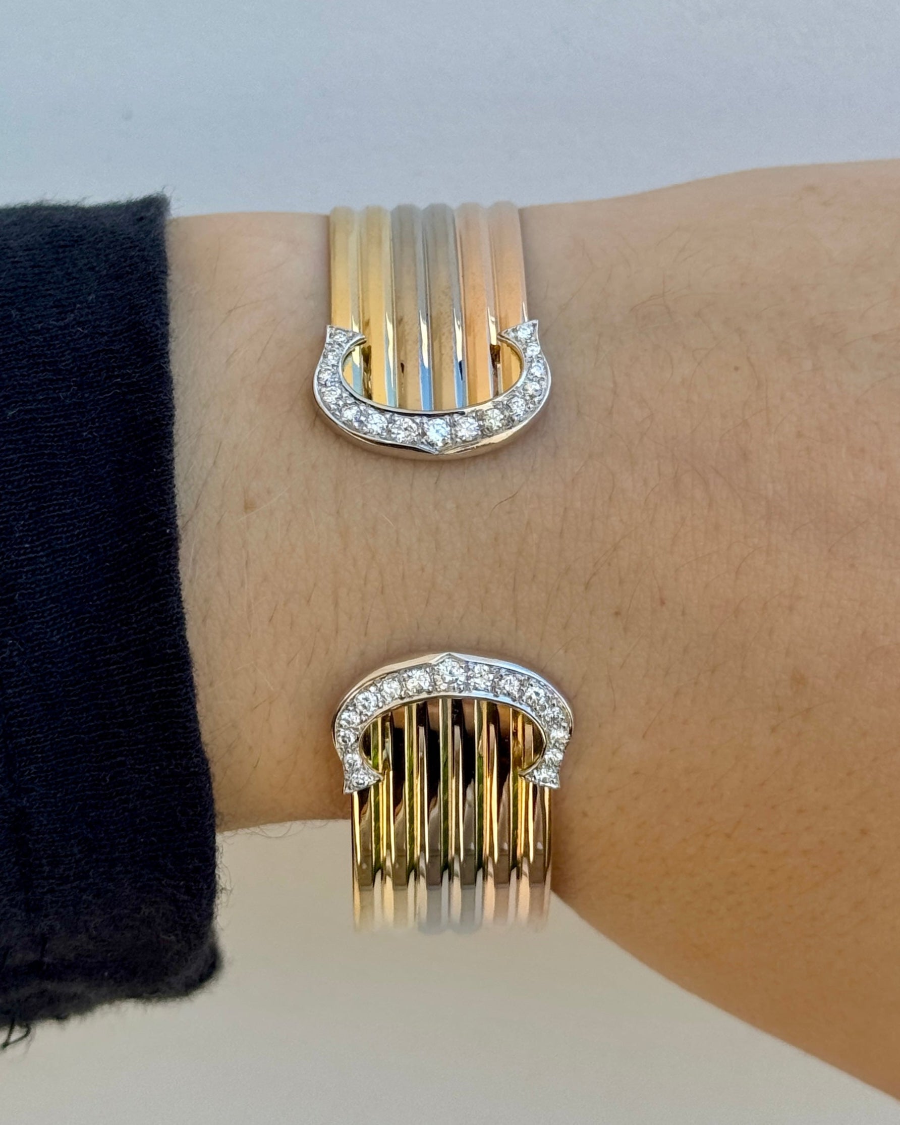 Gold and silver bracelet with fringe design on a wrist against a neutral background