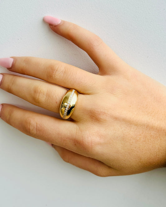 Hand wearing a gold ring on a light background