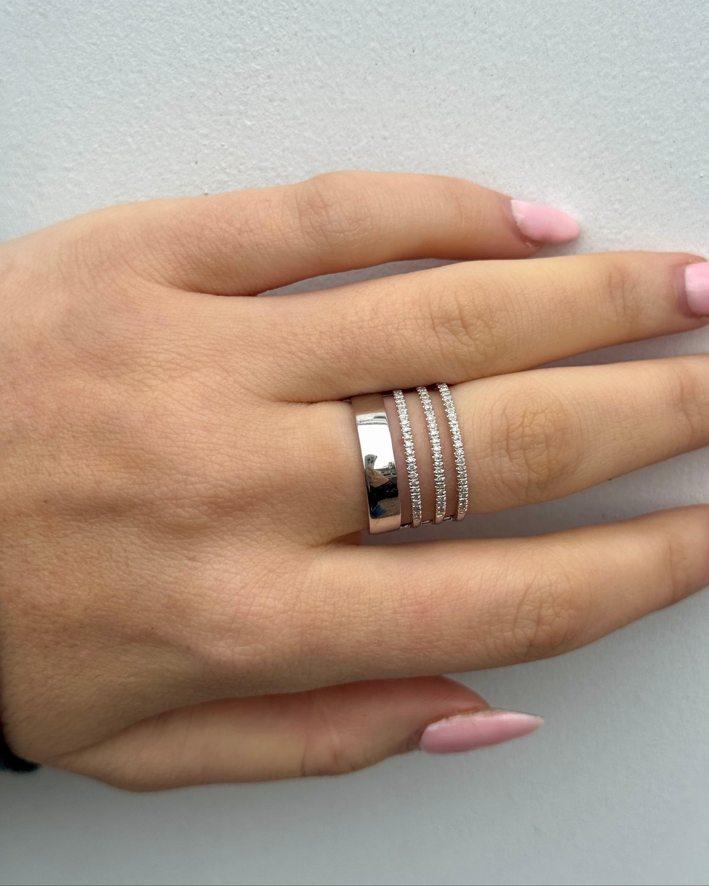 Hand wearing multiple rings on a light gray background