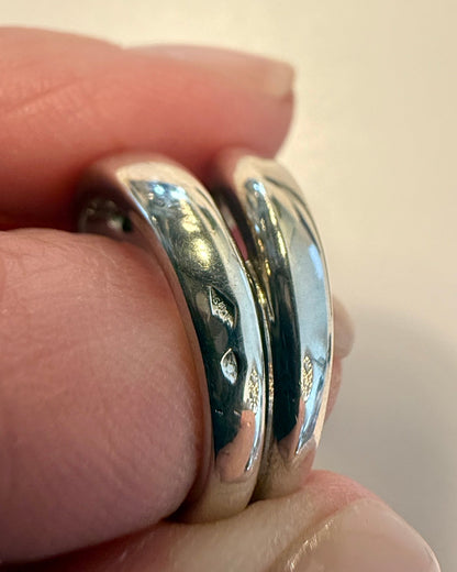 Silver ring being worn on a finger with a plain background