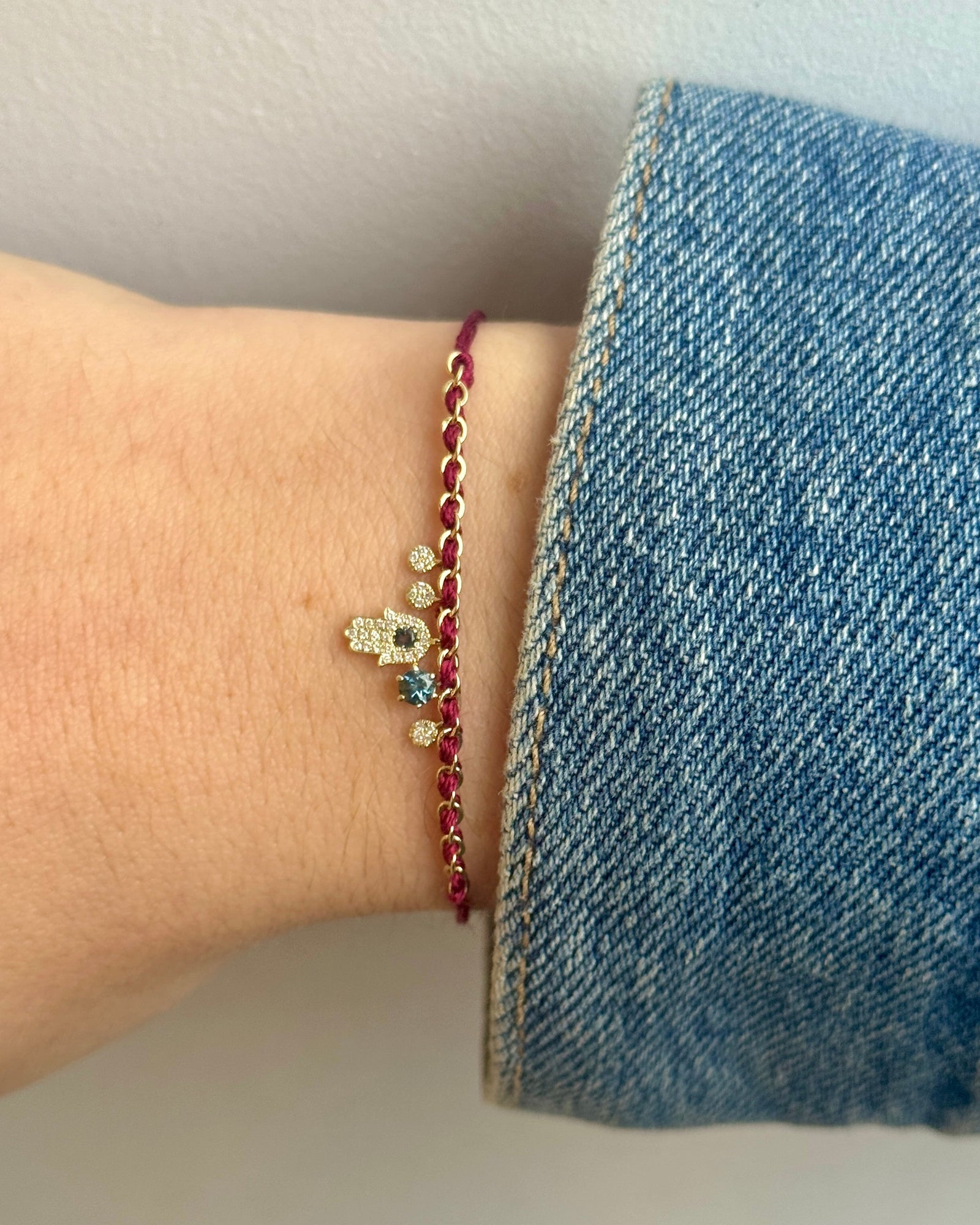 Bracelet with a blue charm on a wrist with denim fabric in the background