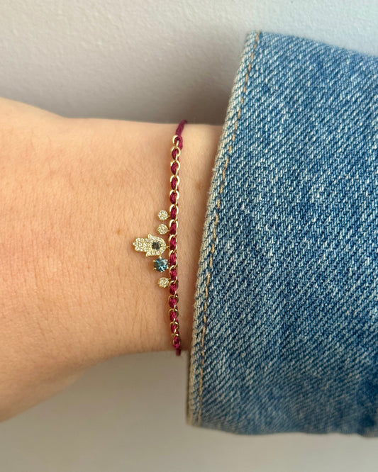 Bracelet with a blue charm on a wrist with denim fabric in the background