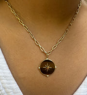 The ANNIE Gold Chain by AIRA, a 16" yellow gold link chain with an extender, elegantly drapes around the neck. Its circular pendant features a star design for celestial charm. The 8mm x 3mm links balance bold style with sophistication.