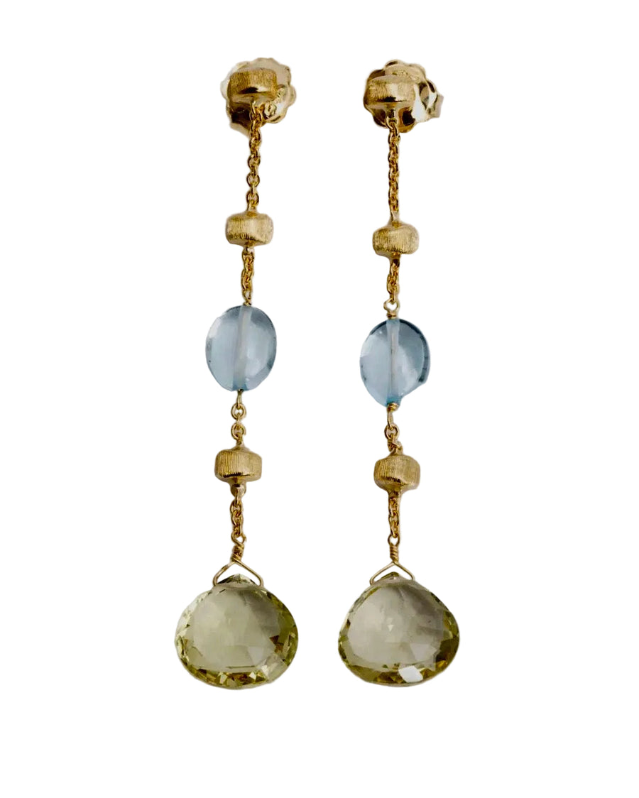 Pair of gold earrings with gemstones on a light gray background