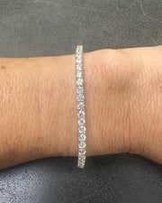 Close-up of a wrist adorned with the DANI Tennis Bracelet by dylan james jewelry, crafted from 925 Sterling Silver and Cubic Zirconia against a dark background.
