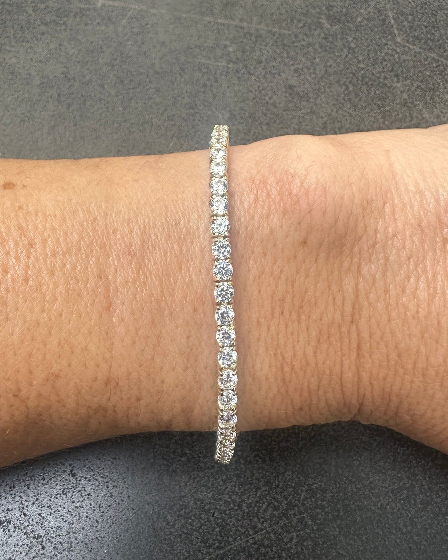 Close-up of a wrist adorned with the DANI Tennis Bracelet by dylan james jewelry, crafted from 925 Sterling Silver and Cubic Zirconia against a dark background.