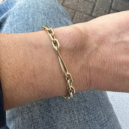 The BARI Gold Bracelet from Dylan James Jewelry elegantly adorns a person's wrist, beautifully complementing their denim jeans.