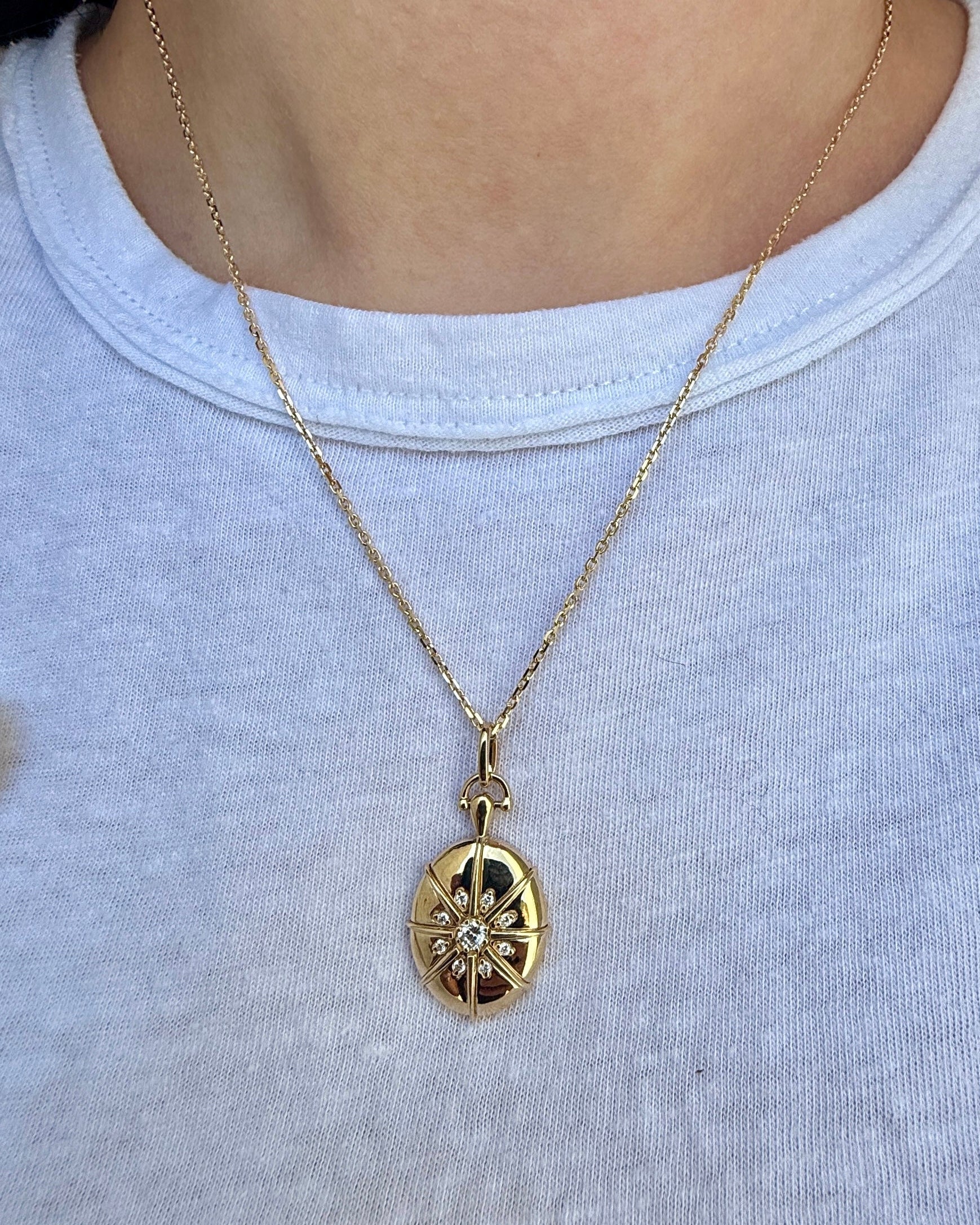 Gold necklace with a pendant worn by a person on a plain background