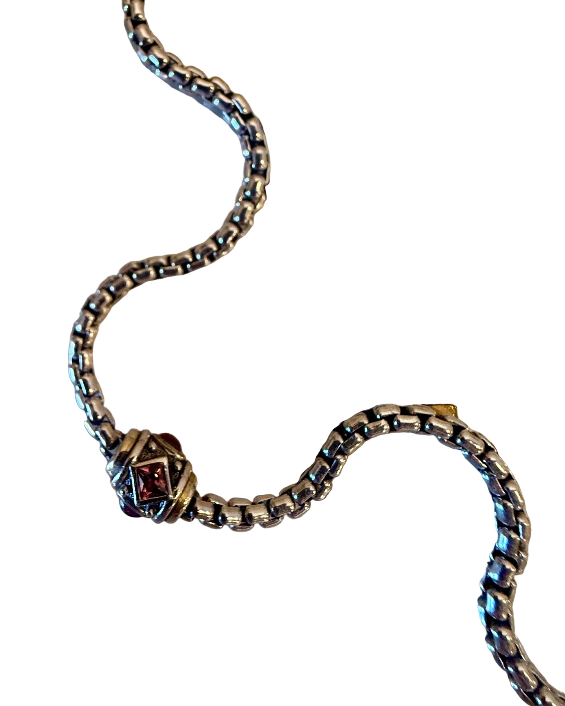Silver chain with a clasp on a white card with measurement markings