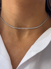 Close-up of a person's neck wearing the KAYLA Tennis Necklace by Dylan James Jewelry, featuring sparkling cubic zirconia and paired with a white collared shirt.
