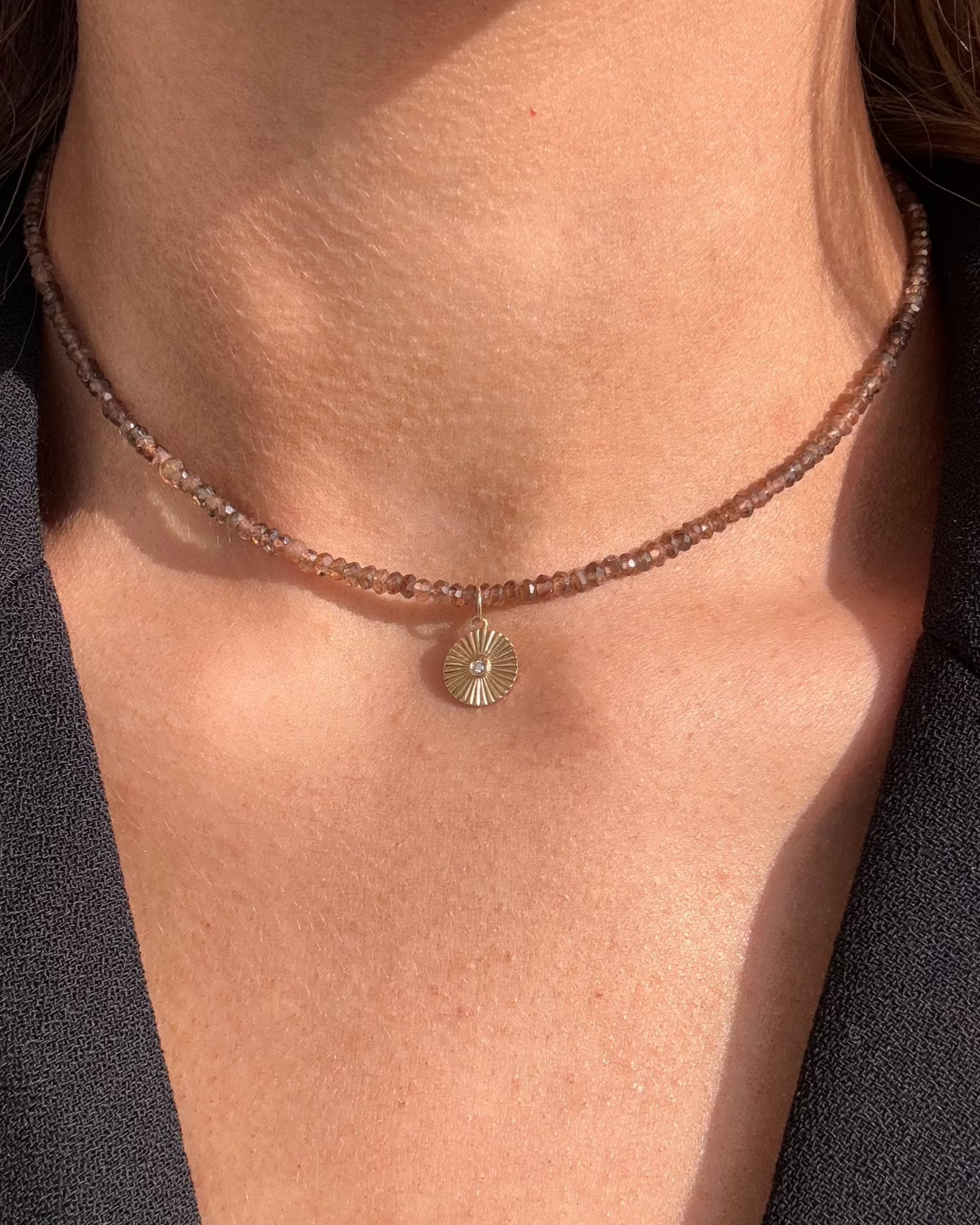 Close-up of a person wearing the JASPER Beaded Diamond Necklace by Dylan James Jewelry, featuring a small round charm pendant, over a black textured garment.