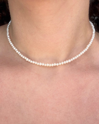 Pearl necklace worn by a person with a blurred background