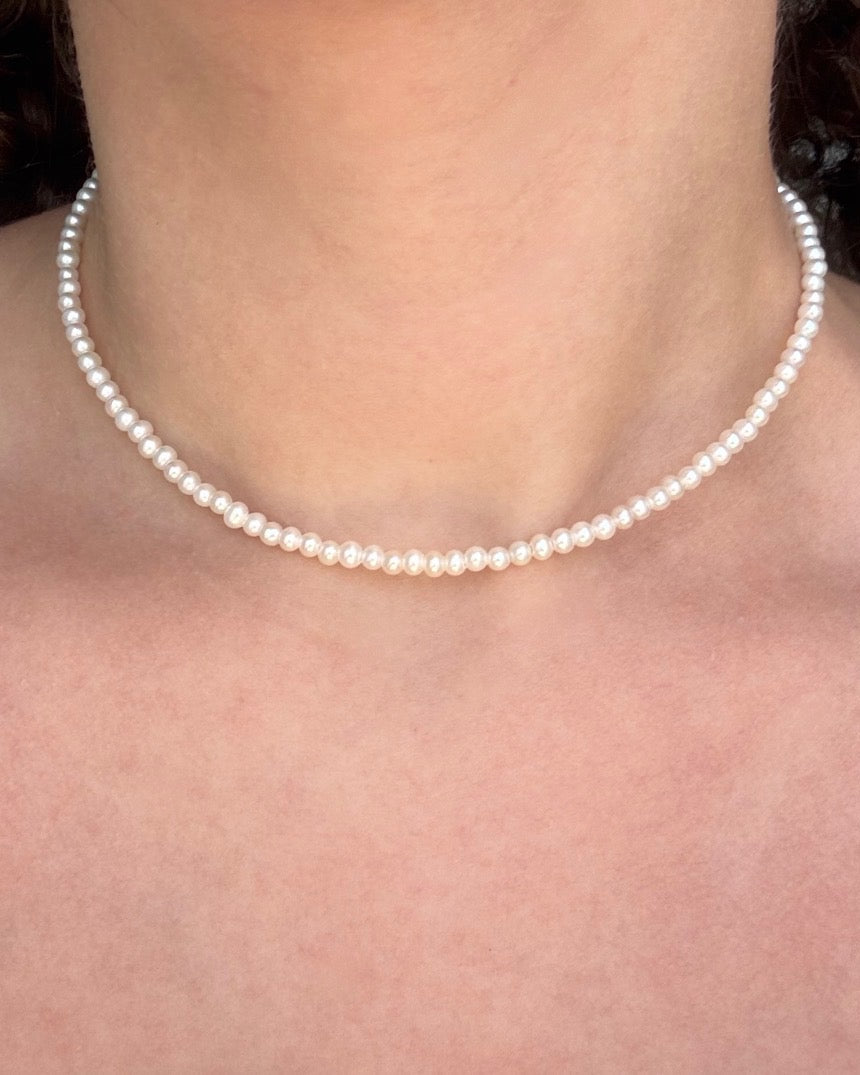 Pearl necklace worn by a person with a blurred background
