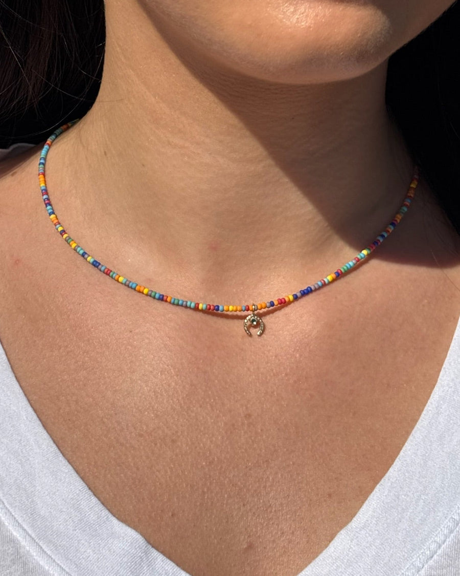 Close-up of a woman wearing a colorful beaded necklace and earrings.