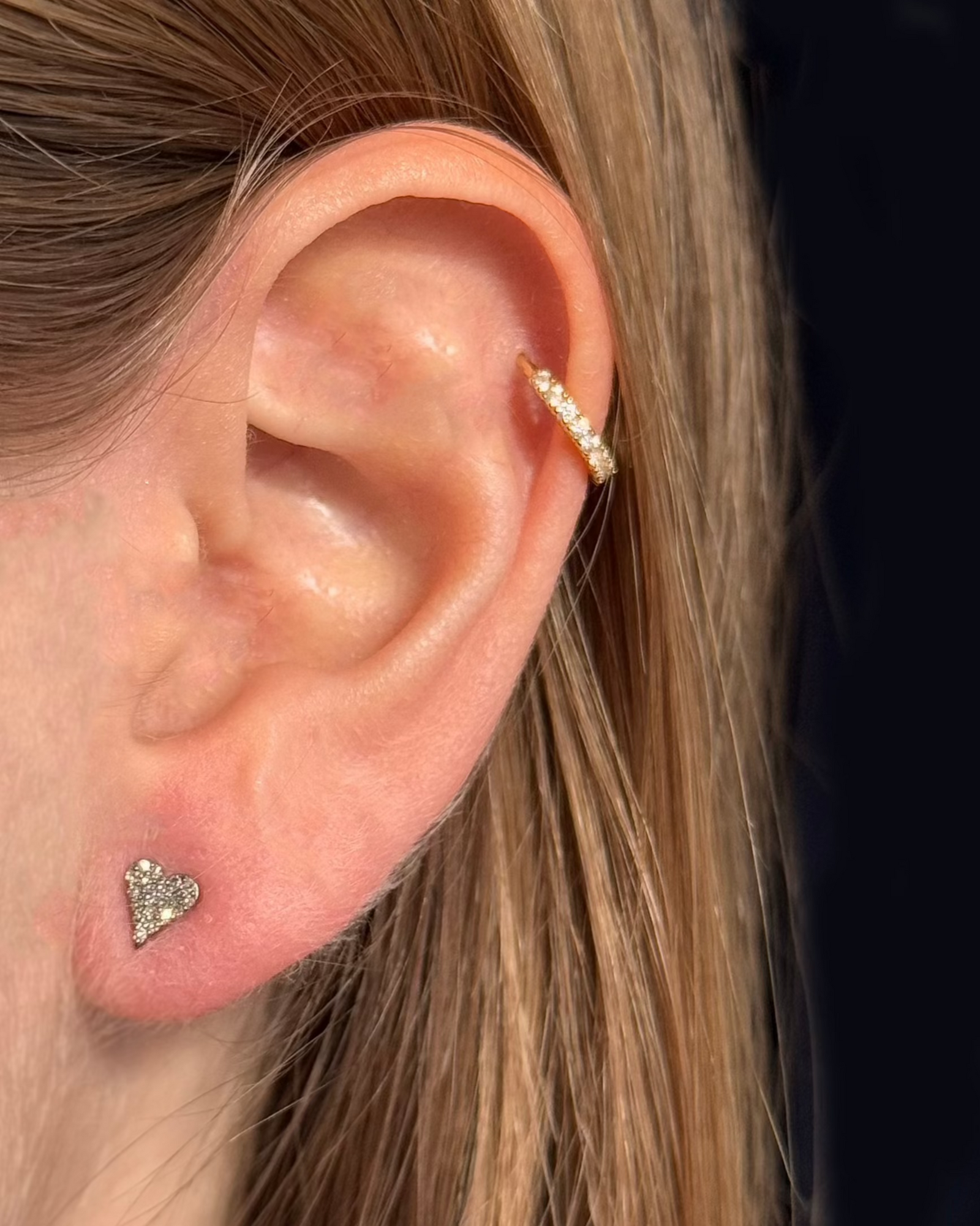 A close-up of an ear highlights a small 5 x 6 mm AUDREY Silver Diamond Stud by Dylan James Jewelry in the lobe, complemented by a sleek ring in the cartilage.