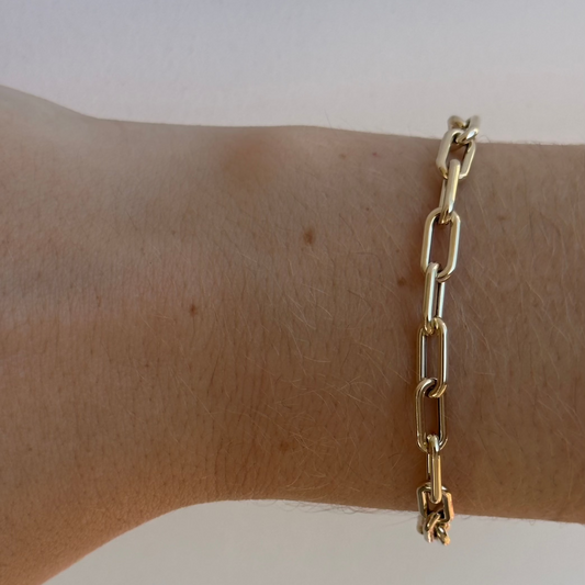 The JERI Gold Bracelet by Dylan James Jewelry, crafted in 14kt yellow gold and measuring 7 inches, graces the wrist with its elegant elongated links against a light background.