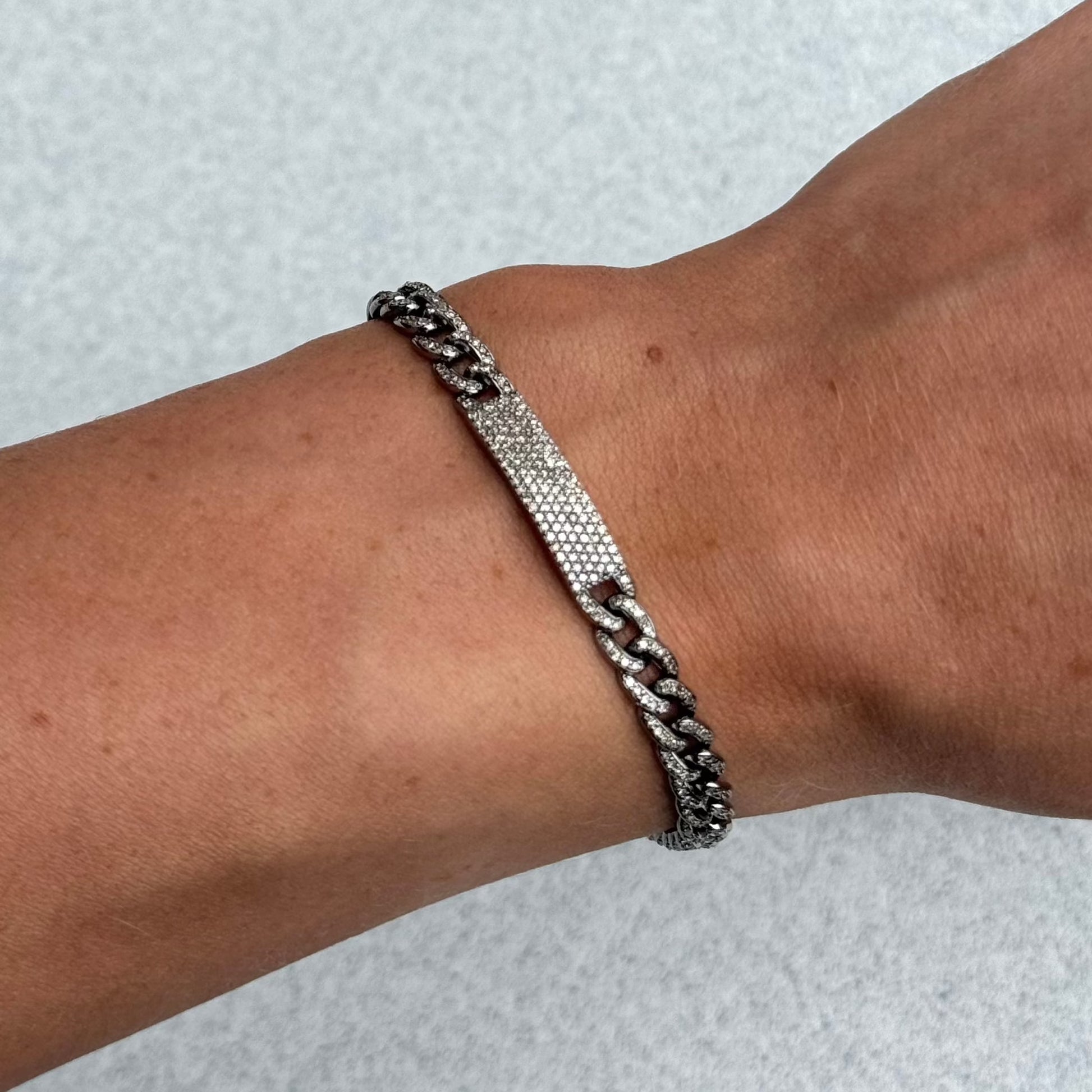 The AYZ Bracelet by Dylan James Jewelry, crafted from sterling silver, elegantly adorns a person's wrist and glimmers against a light gray background.