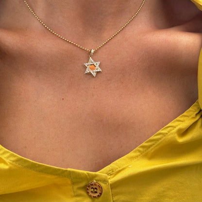 Close-up of a person wearing the KEBE Gold Diamond Star necklace by Dylan James Jewelry, crafted from 14kt yellow gold with a star-shaped pendant on a delicate ball chain, set against the background of a yellow buttoned top.