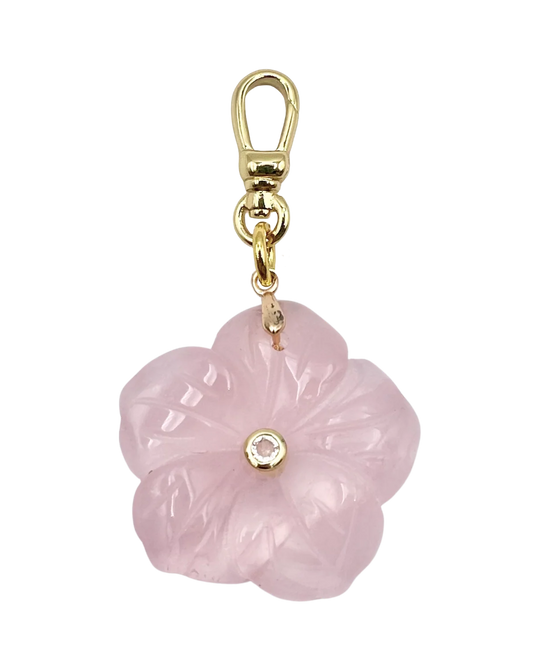 Pink flower-shaped charm with gold accents on a white background