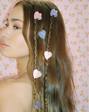 Woman with braided hair adorned with heart-shaped hair clips against a floral background