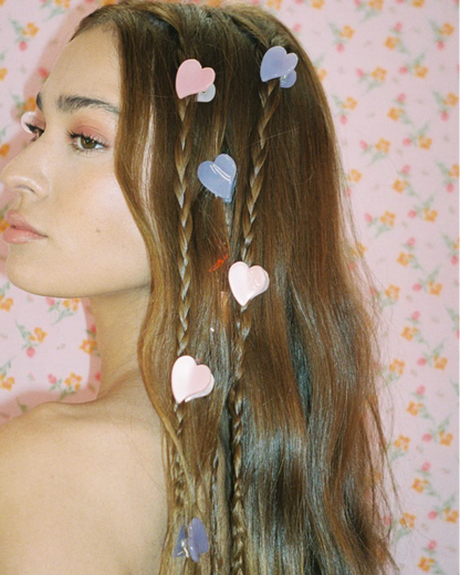 Woman with braided hair adorned with heart-shaped hair clips against a floral background