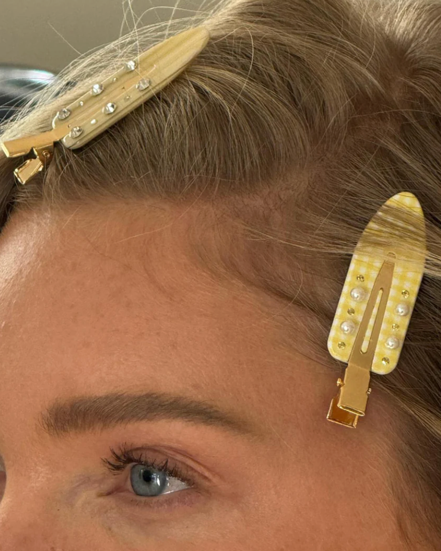Close-up of a person's head with gold hair clips featuring rhinestones.