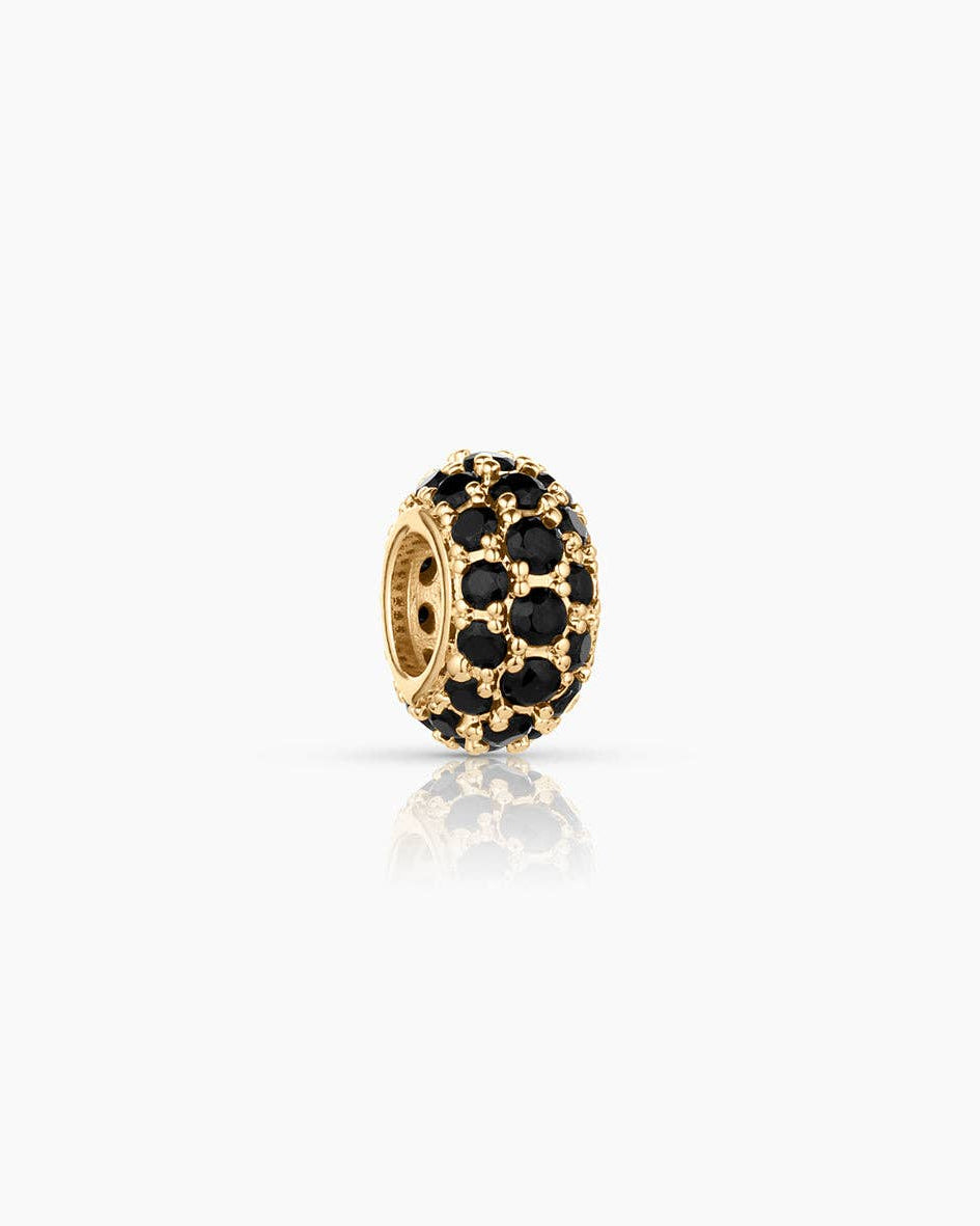 Gold charm with black stones on a white background
