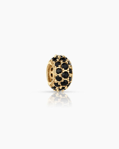 Gold charm with black stones on a white background