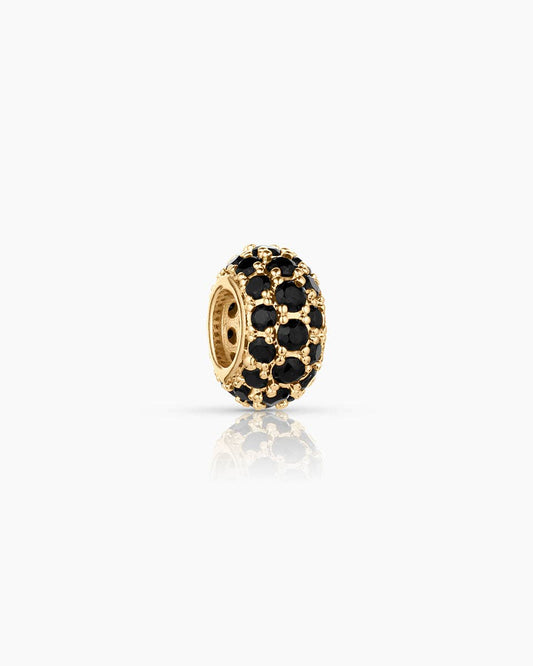 Gold charm with black stones on a white background
