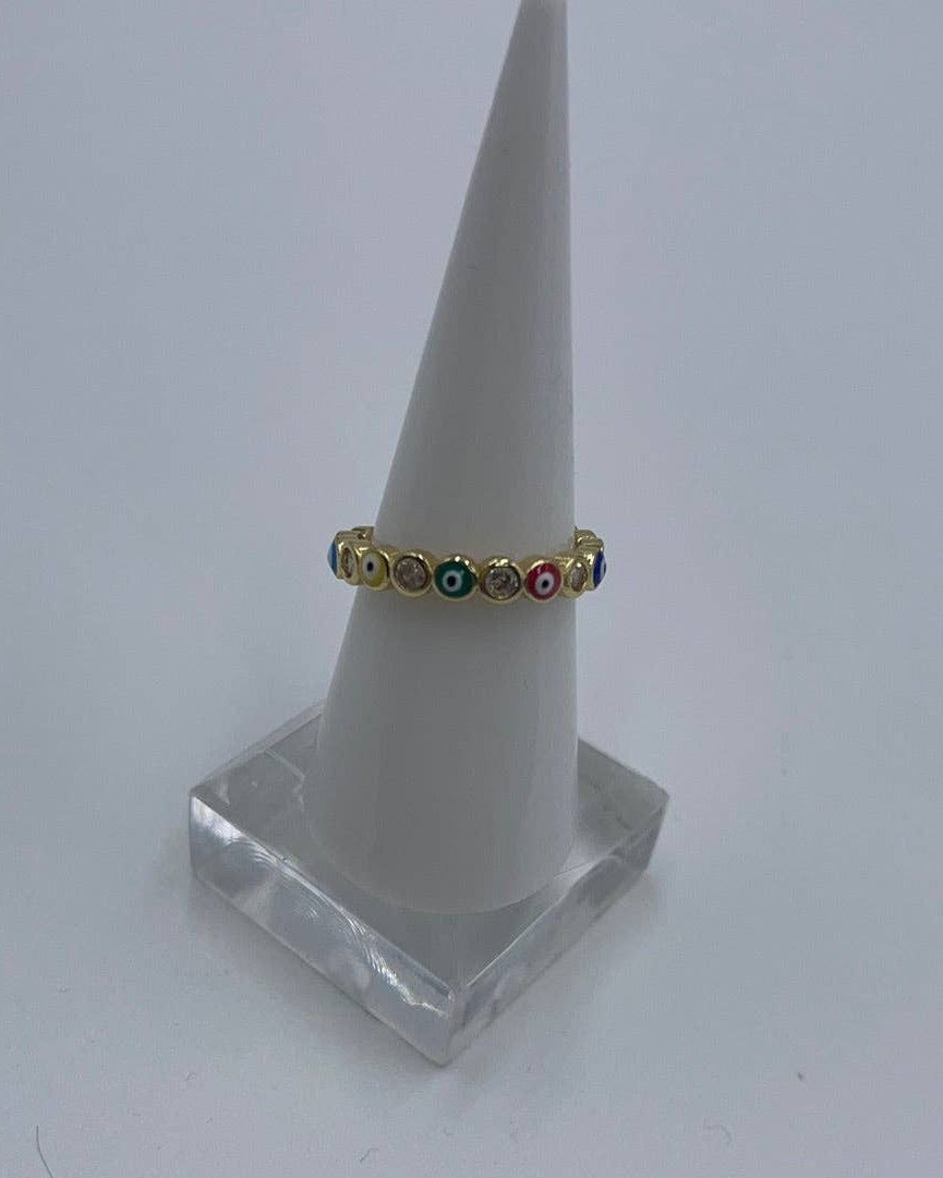 Gold ring with colored stones on a white cone stand against a light gray background