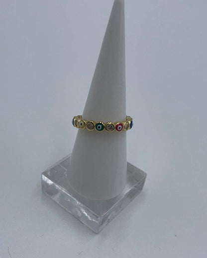 Gold ring with colored stones on a white cone stand against a light gray background