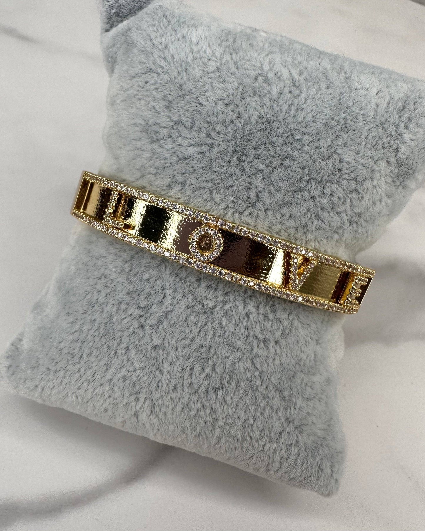 Gold bracelet on a gray pillow