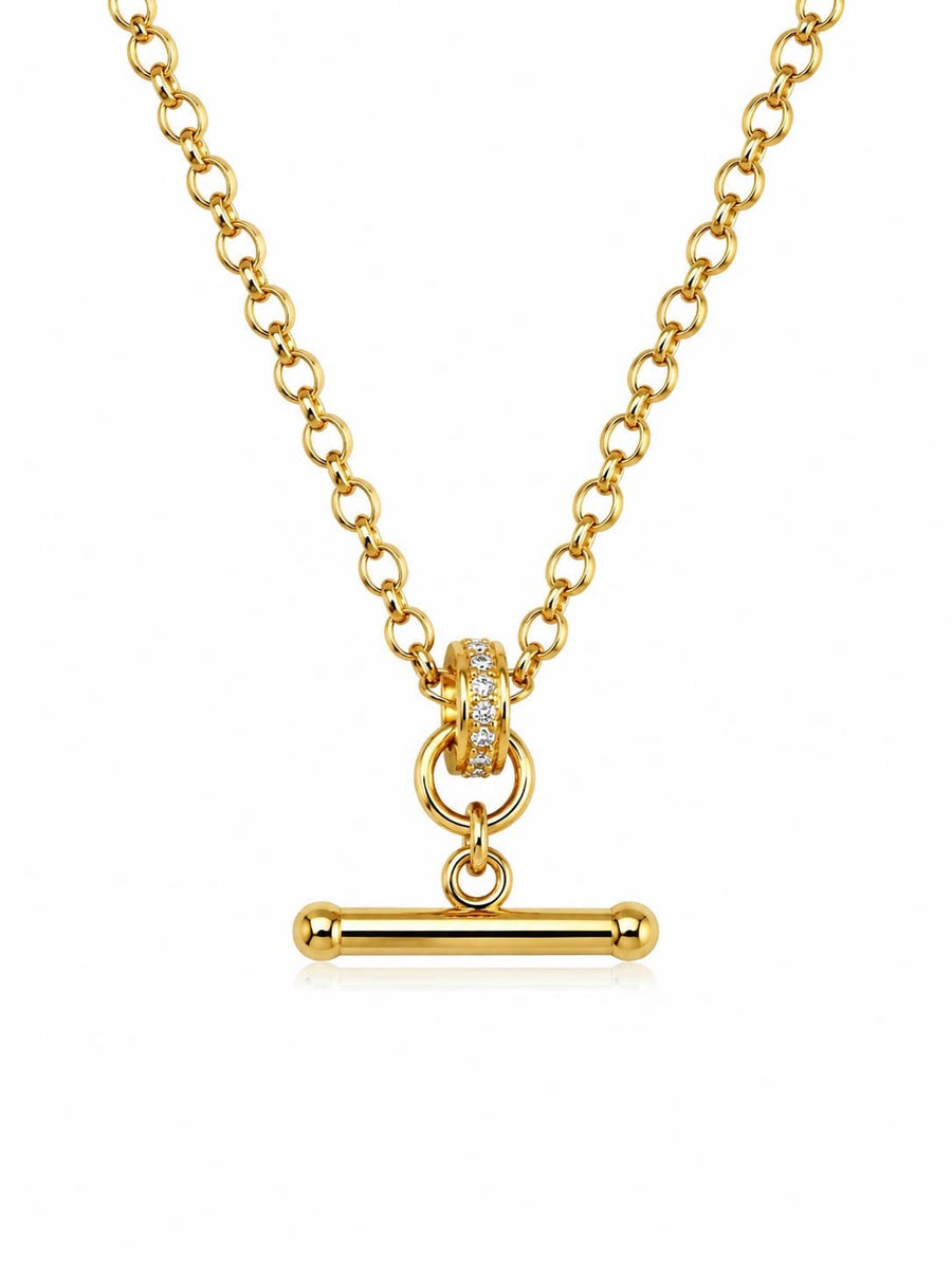 A gold chain necklace with a toggle bar pendant, featuring a small ring of clear stones on the clasp, set against a plain white background.