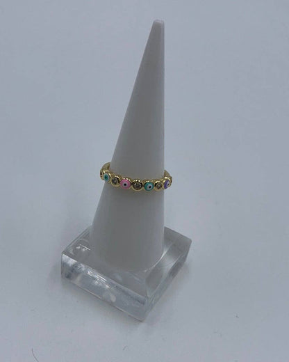Gold ring with colorful stones on a white cone-shaped stand against a light gray background