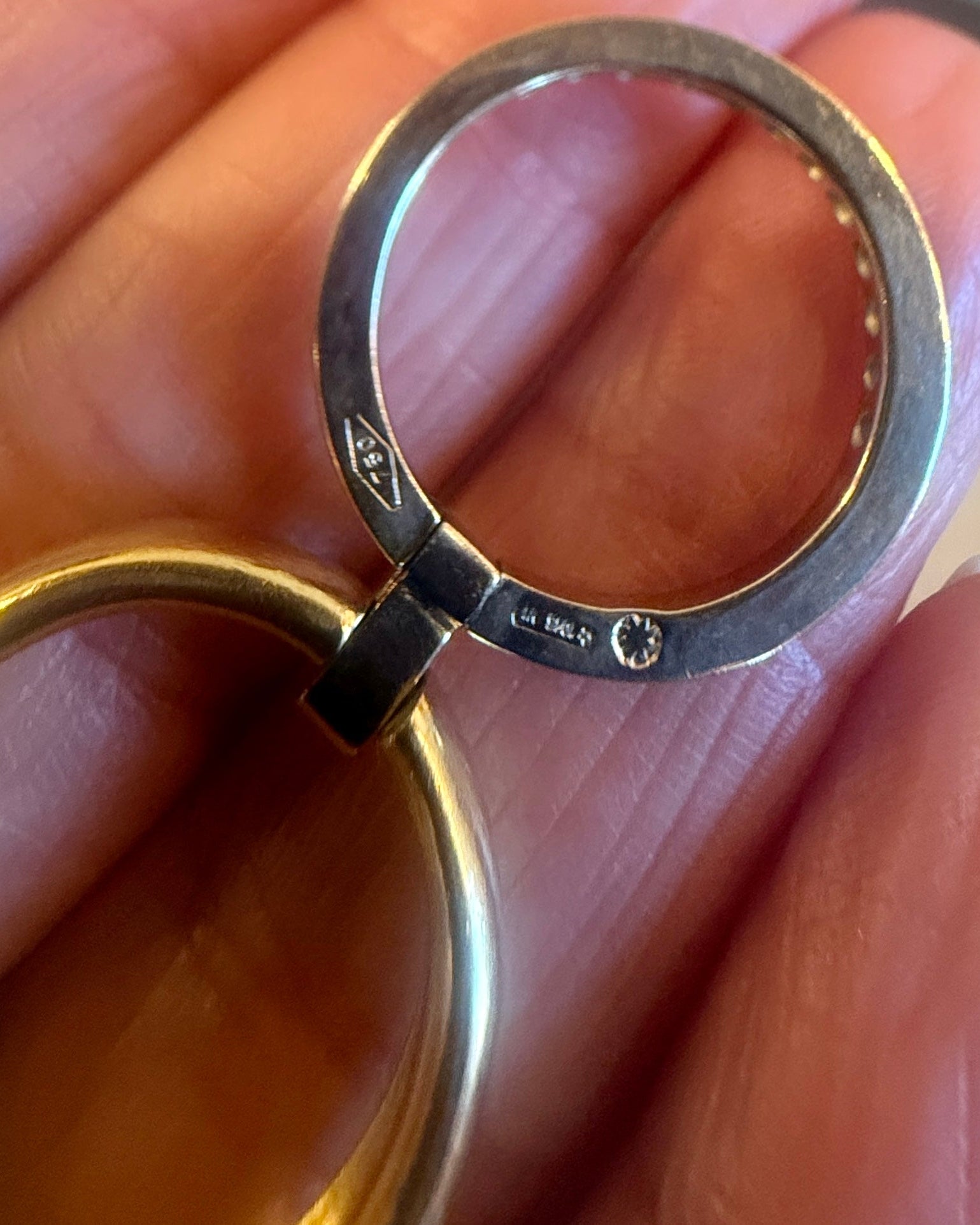 Gold ring held between fingers with visible hallmarking