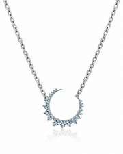 A silver-toned chain necklace featuring a crescent moon pendant adorned with small light blue gemstones, shown on a clean white background with a subtle reflection below.