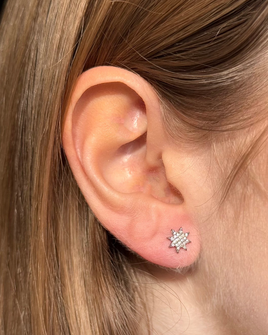 Close-up of an ear wearing the 8mm STELLA Silver Diamond Studs by Dylan James Jewelry, featuring a star shape adorned with numerous small diamonds.