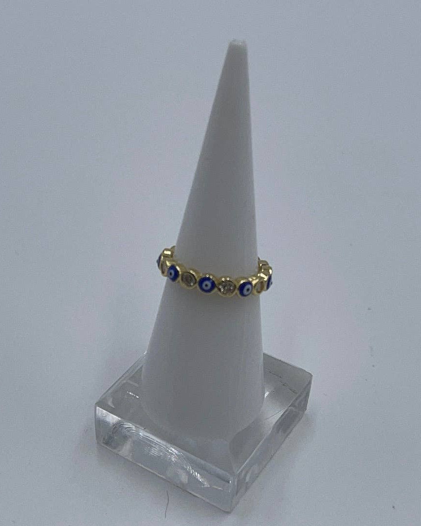 Gold ring with blue stones on a white cone-shaped stand against a light gray background
