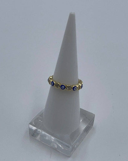 Gold ring with blue stones on a white cone-shaped stand against a light gray background