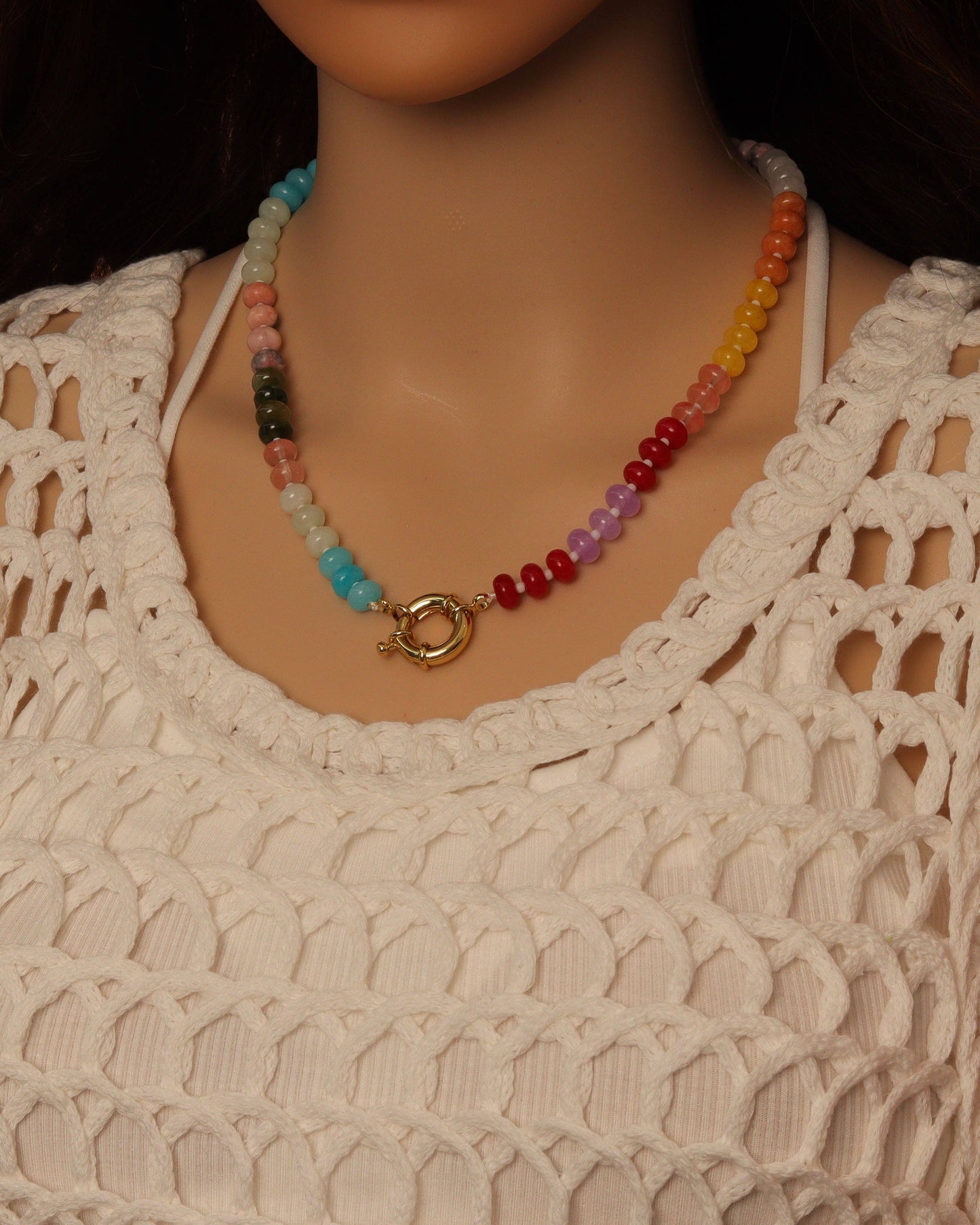 Colorful beaded necklace on a mannequin wearing a beige crochet top.