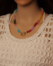 Colorful beaded necklace on a mannequin wearing a beige crochet top.