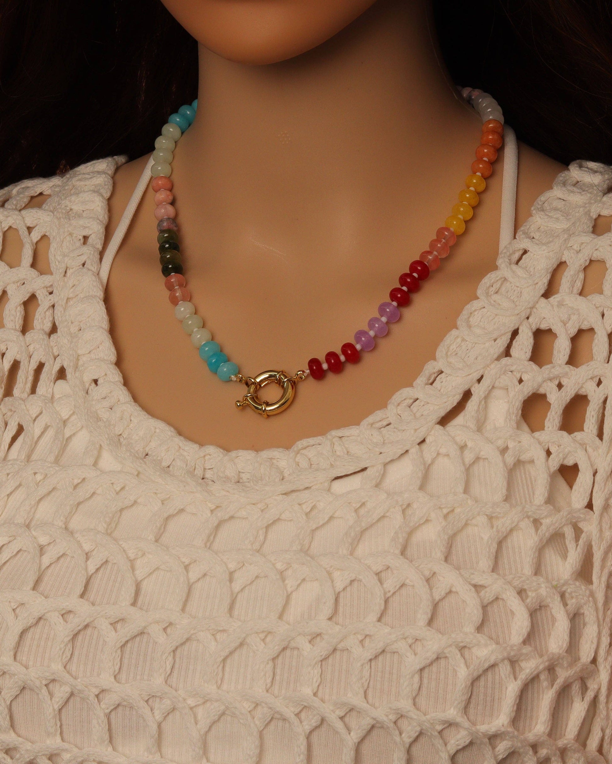 Colorful beaded necklace on a mannequin wearing a beige crochet top.