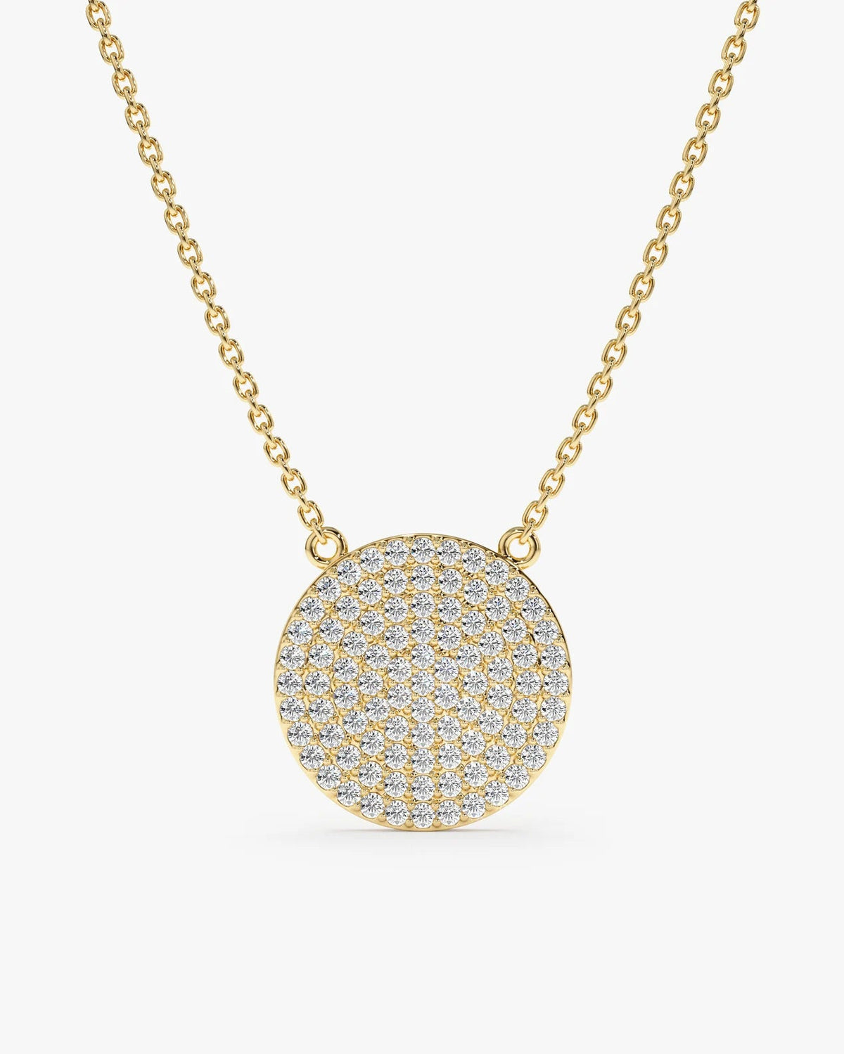 A gold chain necklace with a round, flat pendant paved with small clear stones, shown on a light gray background.