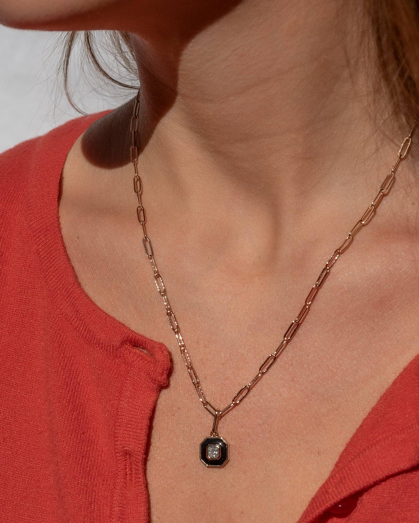 Necklace with a pendant worn by a person in a red top