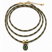 A multi-strand braided cord necklace in olive green with gold-toned metal accents and a teardrop-shaped green gemstone pendant, shown on a plain white background.