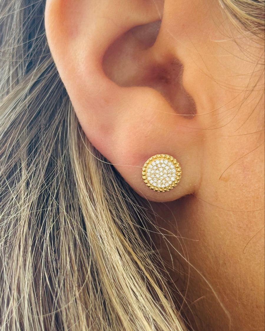 Close-up of an ear wearing a gold earring with a blurred background
