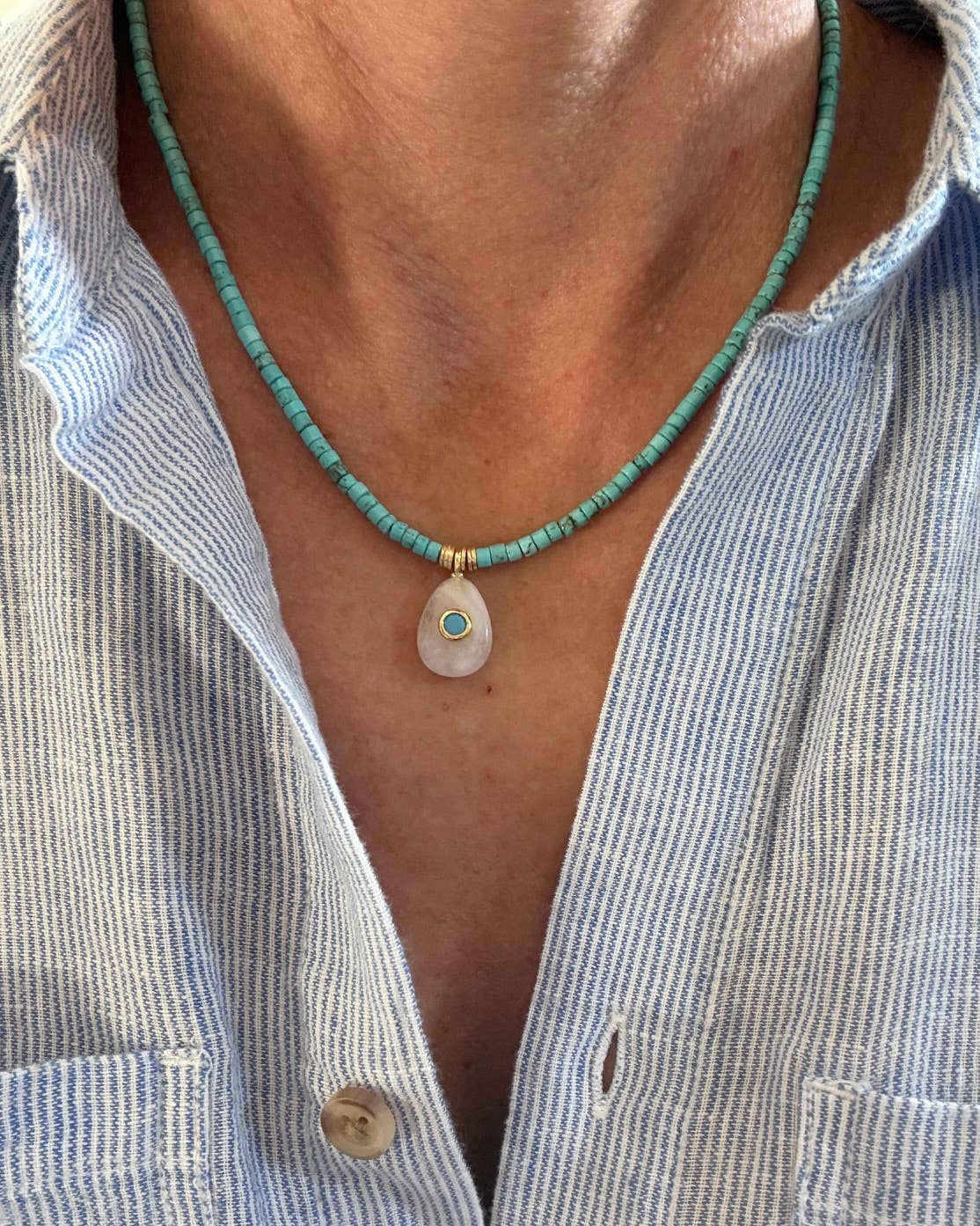 Necklace with a pendant worn by a person wearing a striped shirt