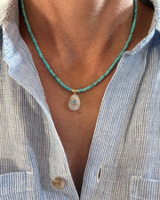 Necklace with a pendant worn by a person wearing a striped shirt